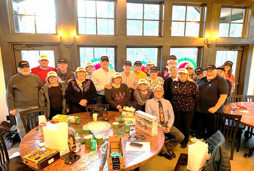 Group standing together in front of large window all wearing similar hats.